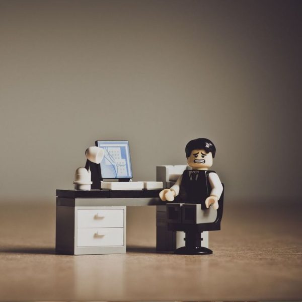 Ludzik Lego siedzi przy biurku i ma nietęgą minę.